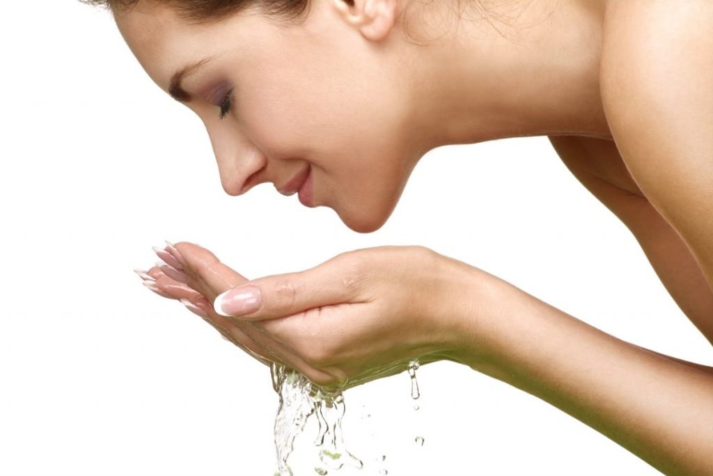 woman refreshing face with water