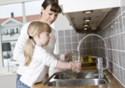 mother giving child drink from sink